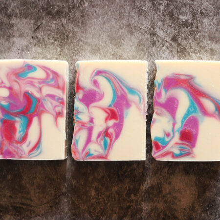 Three bars of soap, sitting laid flat so you can see the swirls of blue, purple, and pink.