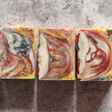 Three soaps laid flat so you can see the swirl. They're a striking mix of black, red, yellow, and white. Very dramatic.