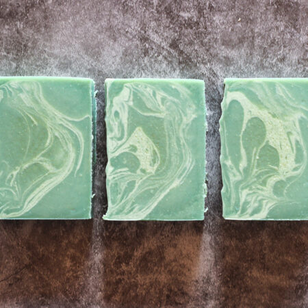 Three bars of green soap with a lighter swirl throughout, laid flat.