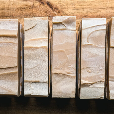Bars of creamy soap, tan coloured, lined up to show the tops of the bars. They've been smoothed with the back of a spoon.