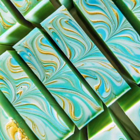 Top down photo of a green soap with blue and gold swirling through the surface.