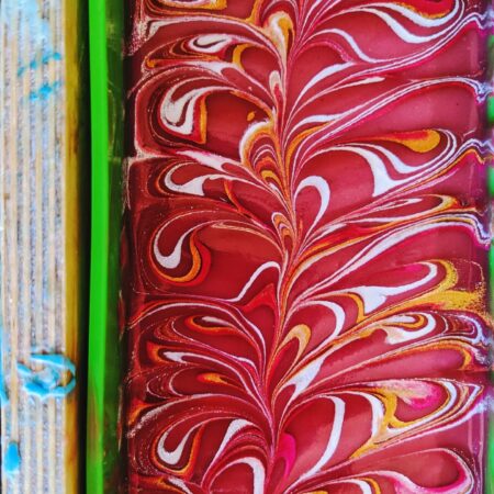 Wet soap in a mould. The soap is bright dark pink, with gold and silver swirling on top.