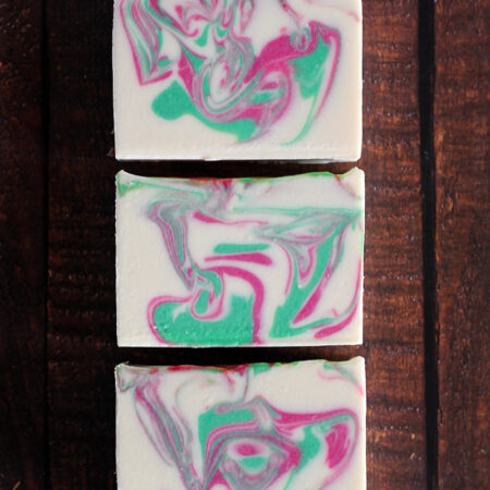 Three bars of soap, showing off the swirls inside. The soap is white, with pink and green swirled throughout.