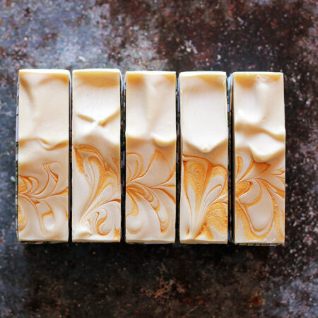 Top down photos of creamy yellow white soap with gold swirls on the top.