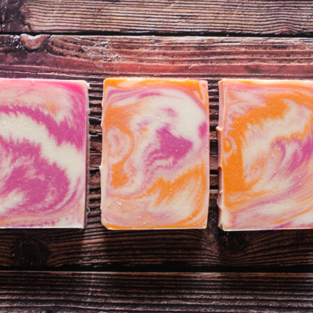 Three bars of soap, swirled with white, orange, and pink