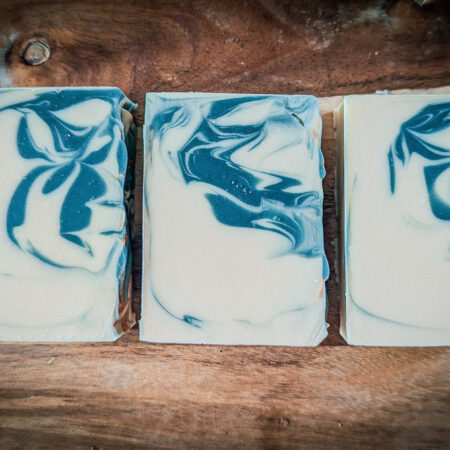 Three bars of soap laid flat so you can see their swirl. They're creamy white, with a deep green swirl inside.