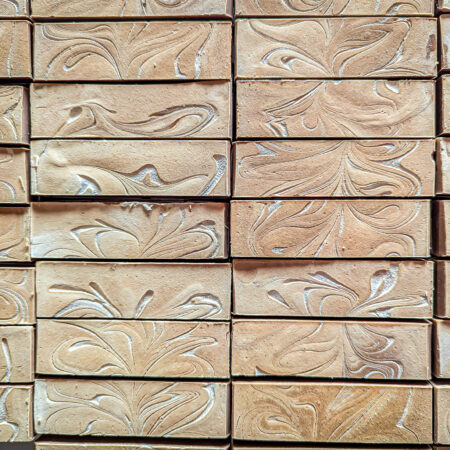 Many bars of soap lined up so you can see the surface swirls on all of them. They're brown, with a silverish swirl.