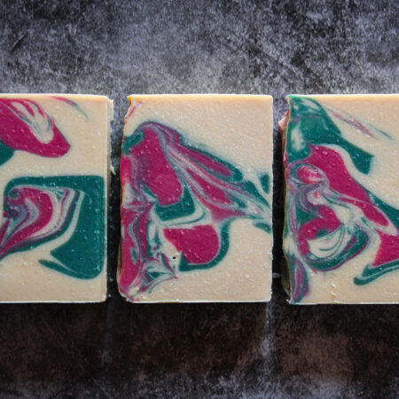 White creamy soap with swirls of pink and dark green in a flat lay style.