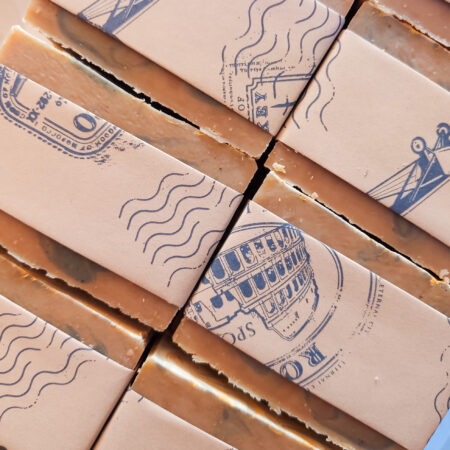 Bars of brown soap in kraft paper bands with blue vintage style print on it.
